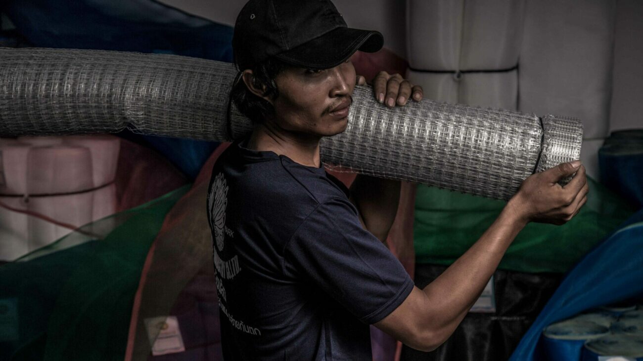 ภาพคนงานของบริษัทสยามเน็ตอินดัสตรีส์กำลังแบกสินค้าตะแกรง